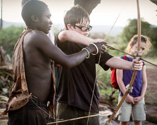 Young-Tourist-Kid-Learning-Bow-Arrow-Hadzabes-Lake-Eyasi-Tanzania